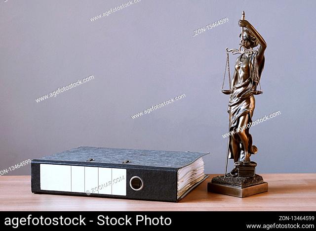 lady justice or justitia statue and file folder on desk - law and legal concept - background with copy space