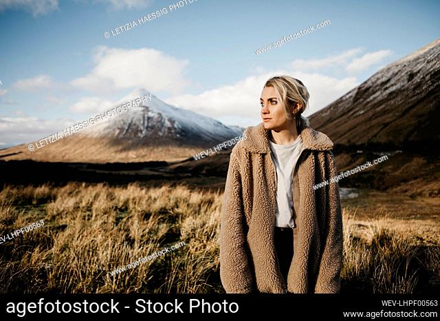 UK, Scotland, Loch Lomond and the Trossachs National Park, pensive young woman standing in rural landscape