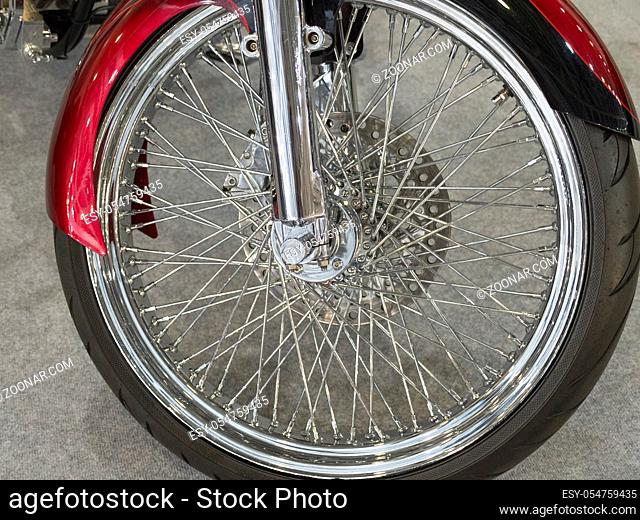 Beautiful nickel plated front wheel of a red motorcycle