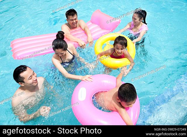 Family and friends playing in the water at the pool with inflatable tubes