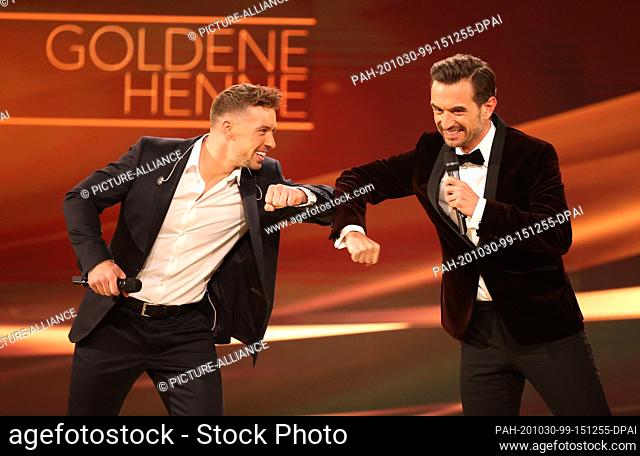 30 October 2020, Saxony, Leipzig: Singer Ramon Roselly (l) and singer Florian Silbereisen are on stage during the TV gala ""Goldene Henne""