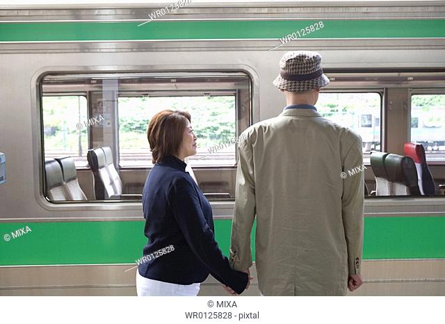 Senior couple standing in front of train