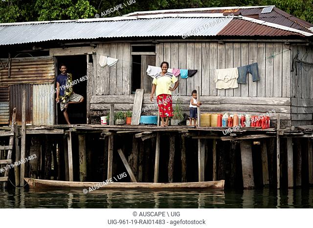 A man, woman and child at a house on stilts above water. Near Kokas, Fakfak regency, McClure Gulf, Papua Province, Indonesia. (Photo by: Auscape/UIG)