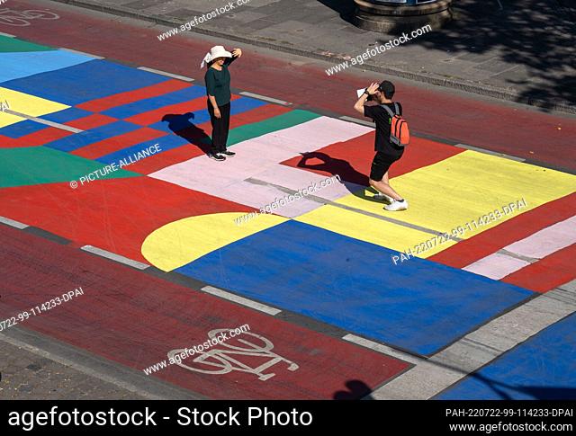 PRODUCTION - 21 July 2022, Hessen, Frankfurt/Main: Tourists use the colorfully painted roadway at the Mainkai for a souvenir photo