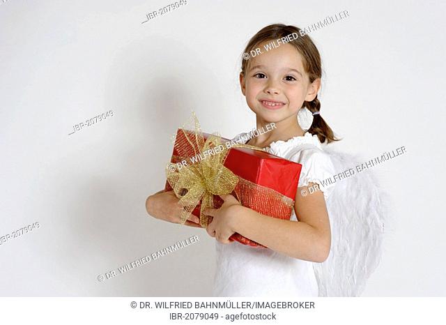 Girl dressed up as a Christmas angel with a gift, Christmas