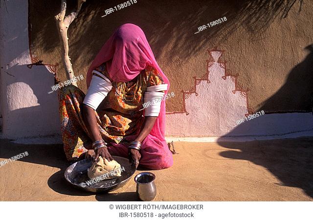 Young Indian woman in sari kneads dough for chapati bread, Thar Desert, Rajasthan, India, Asia