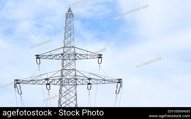 High electricity pole in front of clouded sky