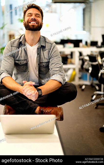 Male entrepreneurhaving a video call on laptop while sitting on table