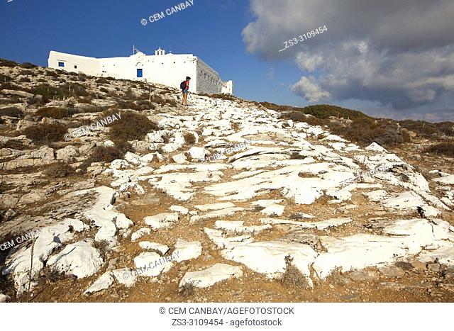 Tourist climbing up to the Zoodohos Pigi monastery situated on the top of the hill at the upper side of the Kastro or Castle village, Sikinos, Cyclades Islands