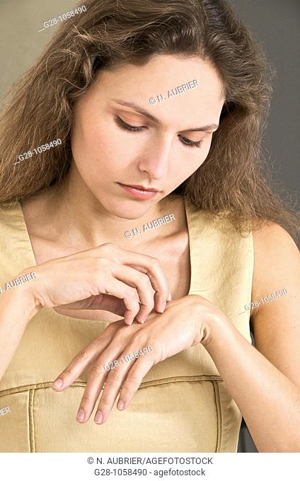 young woman scratching her hand  because of an itching sensation