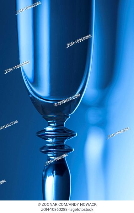 Oberer Teil eines Sektglases vor einem Helligkeits verlaufenden Hintergrund blau getont