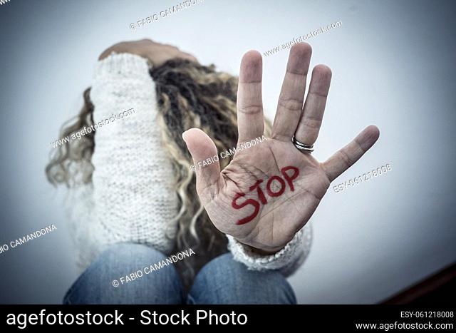 Stop crime violence abuse on women from men - woman protect herself sitting on the ground with hand to defense - home crime violence and couple abueses problems...