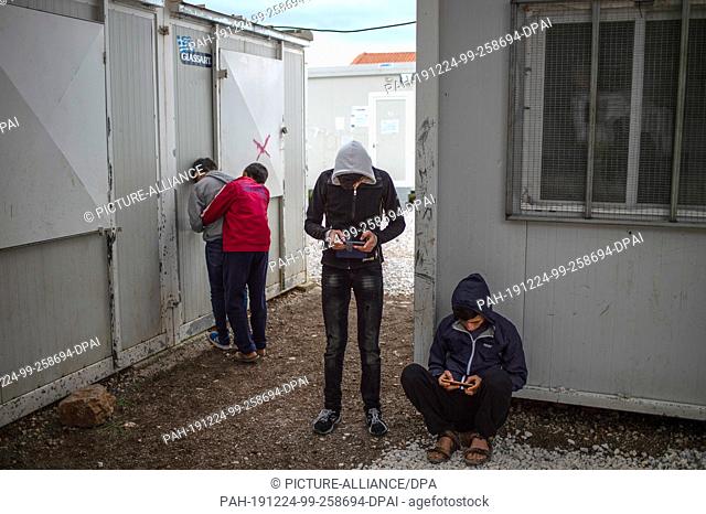 24 December 2019, Greece, Malakasa: Children and young people look at their mobile phones in the refugee camp ""Gerakini"" 42 km from Athens