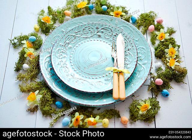 Easter table setting with flowers and eggs. Empty decorative ceramic plates. Rustical dishware. View from above