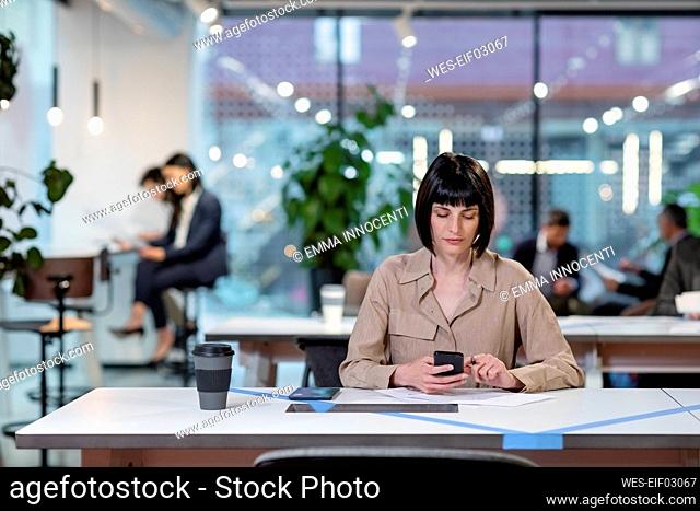 Businesswoman texting on smart phone in office