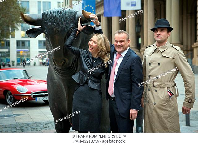 Publishers Birgit (L) and Stefan Luebbe (C) stand next to the sculpture of a bull in front of the stock exchange shortly before the publishing house Bastei...