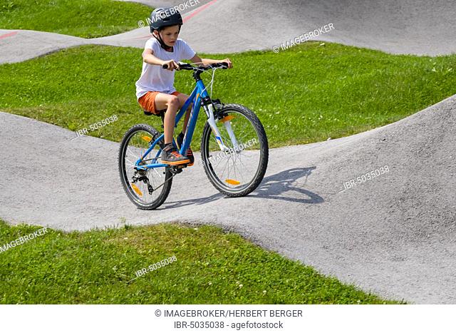 Child, boy, 9 years old riding a mountain bike in a pump track, mountain bike trail, Viehhausen, Salzburg, Austria, Europe