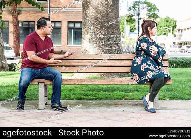 Unhappy Mixed Race Couple Sitting Facing Away From Each Other on Park Bench