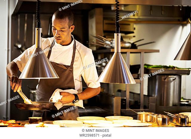 Chef standing in a restaurant kitchen, plating food