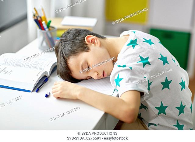 tired student boy sleeping on table at home