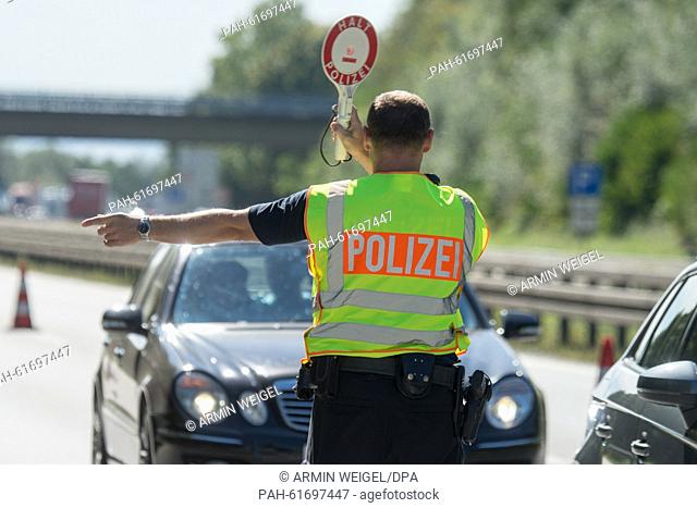A member of the German Federal Police halts a bus for inspection at a checkpoint on the motorway A3 at the German-Austrian border near Pocking,  Germany