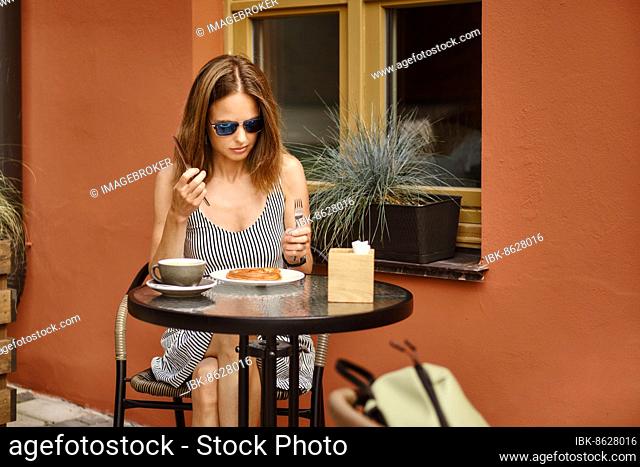 Young woman in sundress is going to have coffee break at outdoor cafe terrace