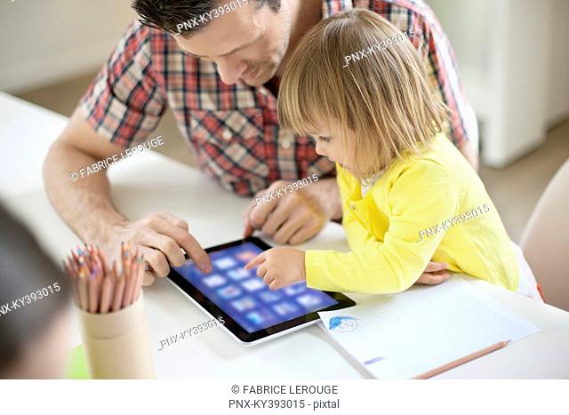 Man teaching digital tablet to his daughter