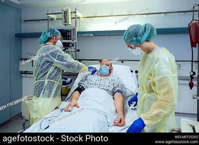 Doctors caring for patient in emergency care unit of a hospital taking temperature