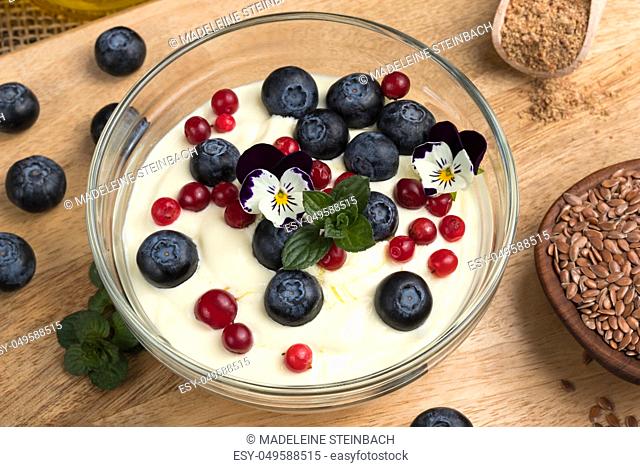 Closeup of cottage cheese blended with flax seed oil, topped with fresh blueberries, frozen wild cranberries and edible flowers
