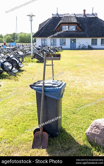 05 June 2020, Mecklenburg-Western Pomerania, Hiddensee: Shovel, broom and garbage can are in the harbour. In the background you can see a thatched house
