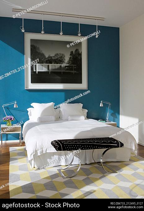 Lamps on bedside tables either side of double bed in modern bedroom