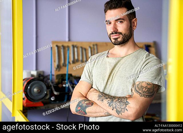 Mid-shot of confident looking bearded bicycle repair shop owner