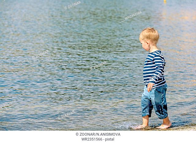 Little preschool boy walking on beach outdoors copy space
