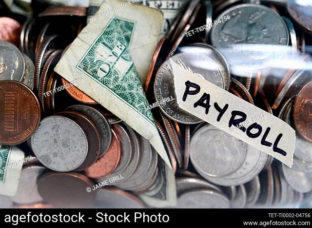 Close-up of coins and banknotes in jar labeled Payroll