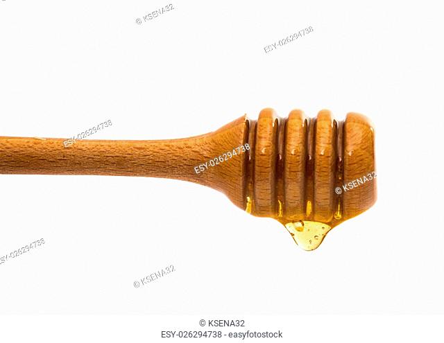 Honey dripping from a wooden honey dipper on white background