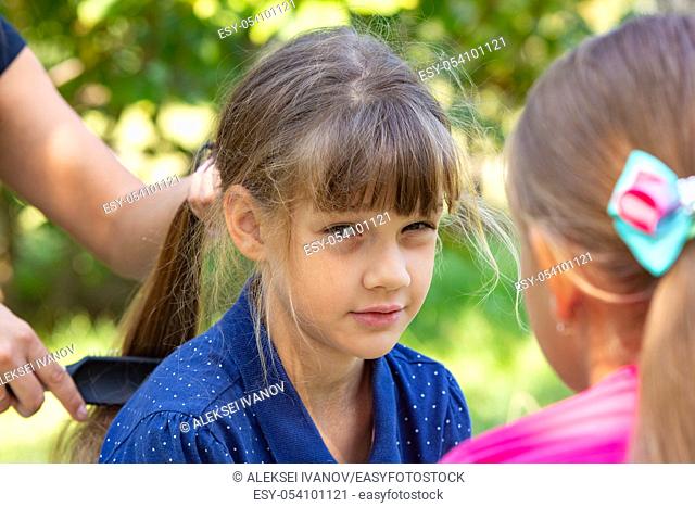 Girl trying to comb the girl's tightly tangled hair