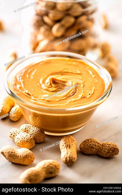 Peanut butter in bowl and peanuts on kitchen table
