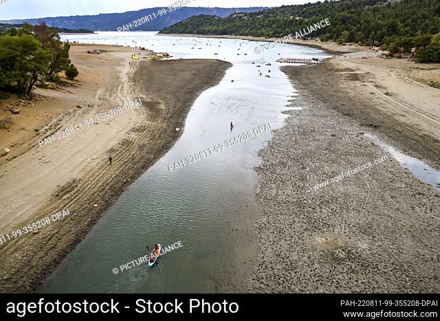 11 August 2022, France, Aiguines: Canoes and SUPs paddle in the meager remnant of the Verdon River at the head of the Lac de Sainte-Croix reservoir