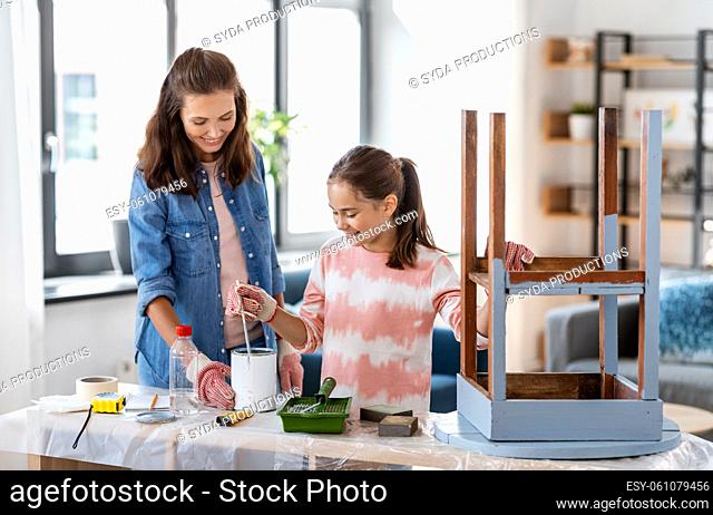mother and daughter stirring grey paint at home