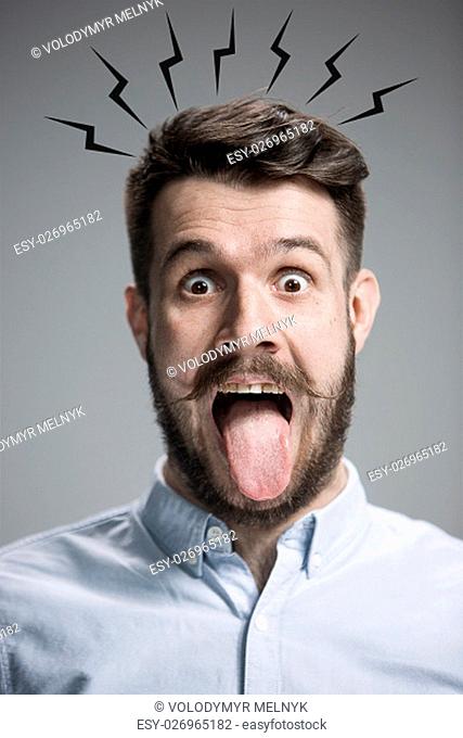 The tongue hanging out man on the gray background. concept of extreme mental stress