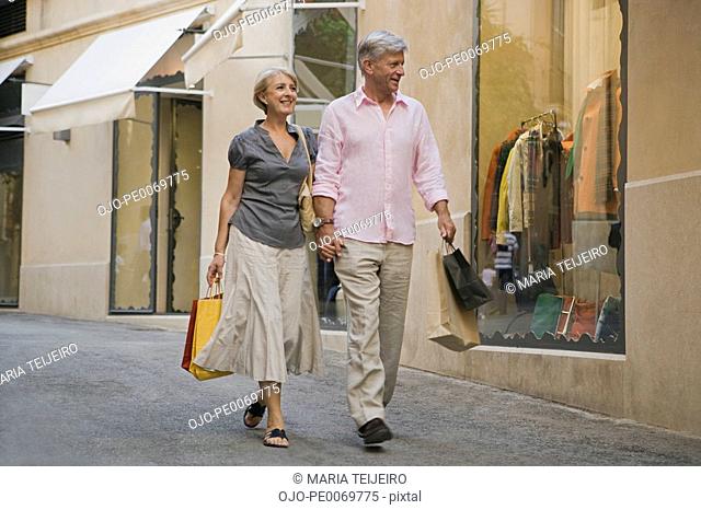 Man and woman holding hands walking with shopping bags