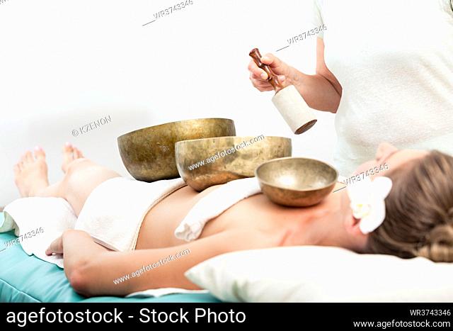 Close-up of a woman lying in spa with copper bowls receiving singing bell sound therapy