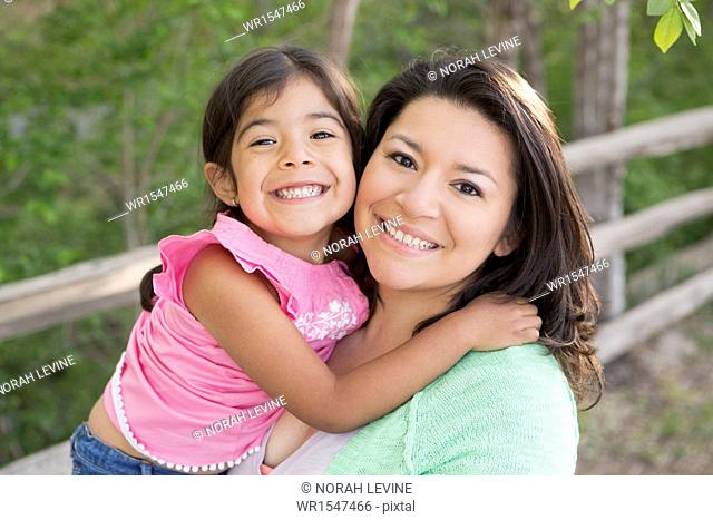 A mother in the park with her daughter, laughing and kissing each other
