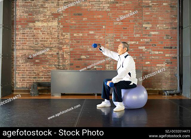 Senior man doing gore training with balance ball