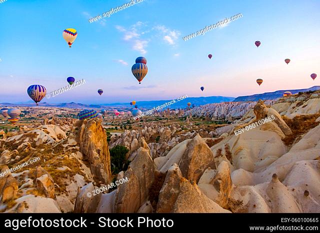 Cappadocia, Turkey - August 31, 2011: Hot air balloon flying over rocky landscape at sunrise in Cappadocia