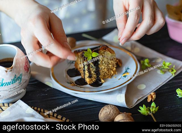 The housewife decorates a piece of cake with green leaves