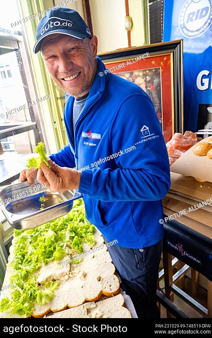 29 October 2023, Mecklenburg-Western Pomerania, Heringsdorf: Axel Schulz, a former professional boxer, covers the gigantic fish roll with lettuce
