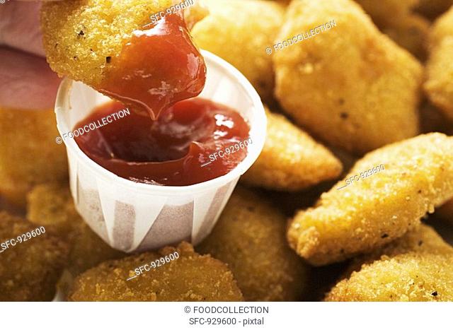 Dipping a chicken nugget in ketchup