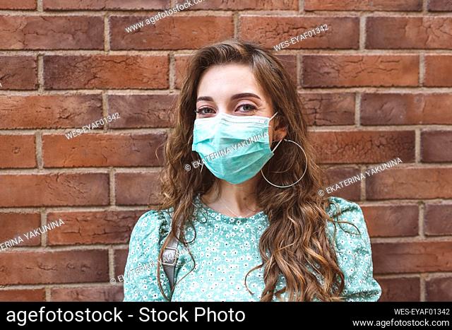 Woman wearing face mask against brick wall during COVID-19 outbreak
