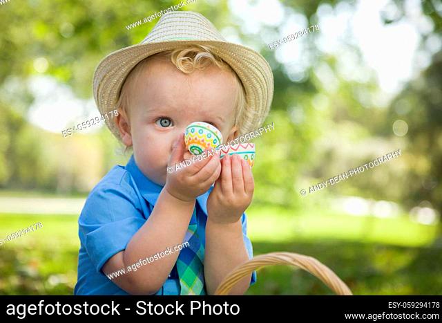 Cute Little Boy Wearing Hat Enjoying His Easter Eggs on Picnic Blanket Outside in the Park